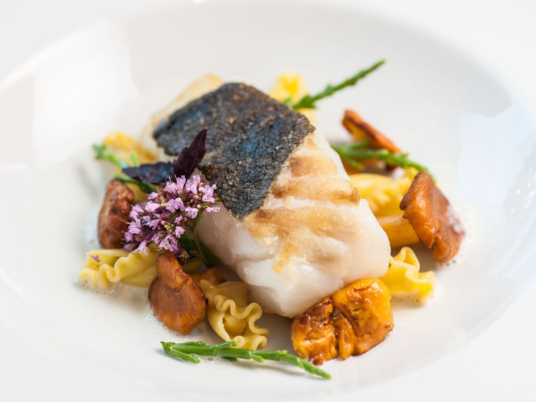 Leckeres Fischfilet angerichtet auf gekochtem Gemüse.