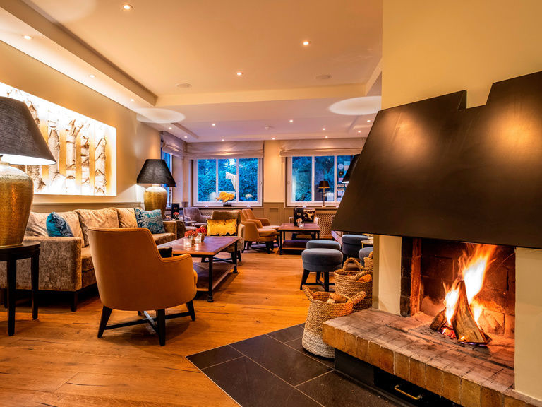 Eine Bar in gemütlicher Atmosphäre mit einem Kamin im Vordergrund.